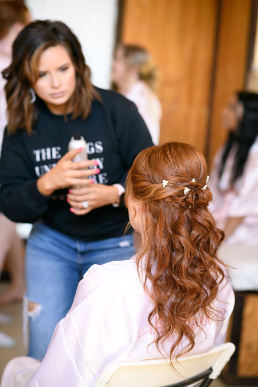 Elegant bridal hairstyle featuring soft waves and braided details being styled for the wedding day.