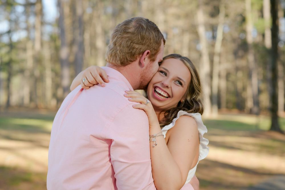 Intimate engagement portrait captured in sunlit forest setting.