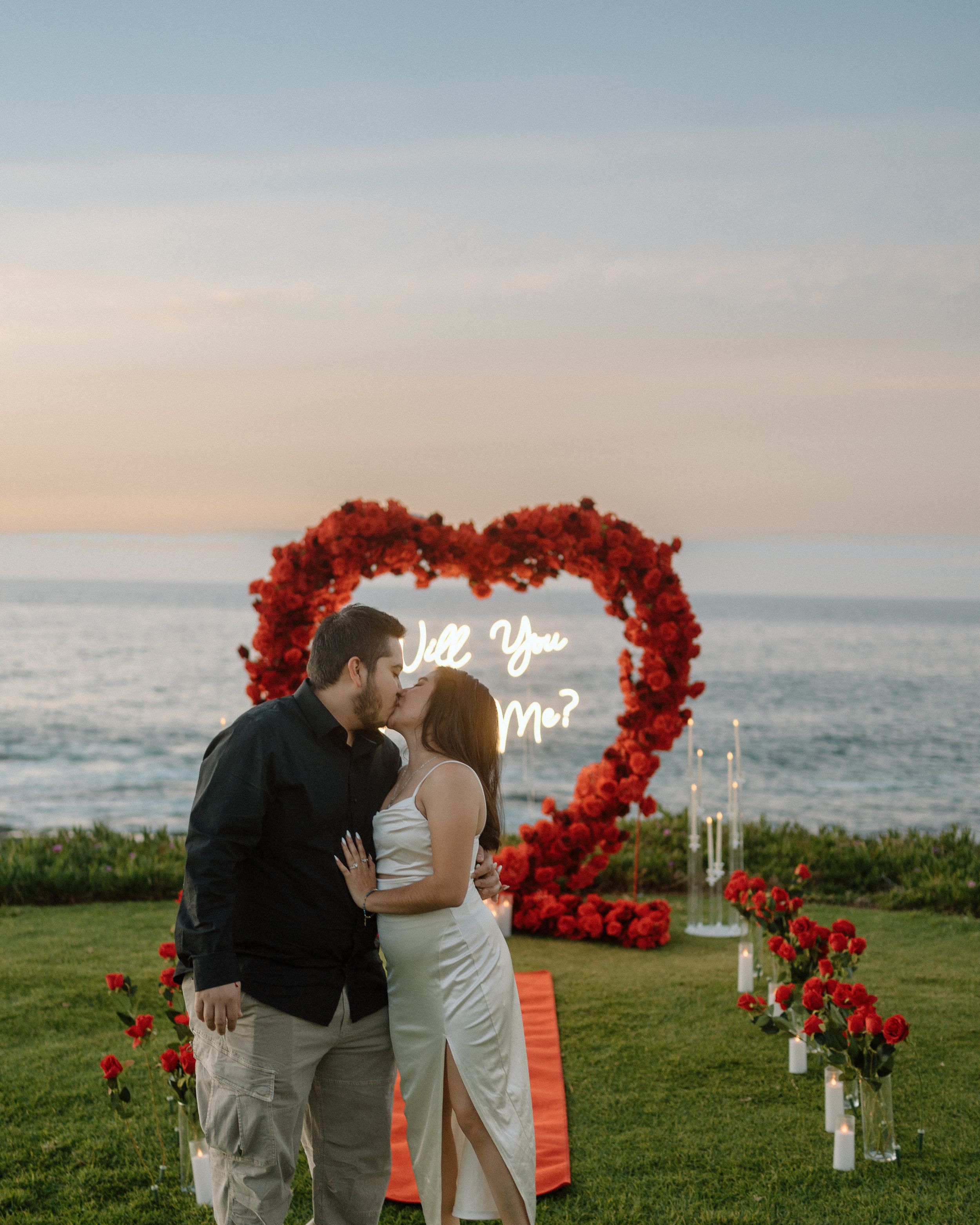 Whimsical beach engagement session in San Diego. Fun, creative couples photography capturing love and joy with a heart-shaped floral wreath