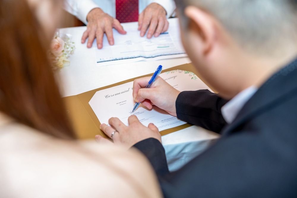 Close-up of people signing documents together with a blue pen.