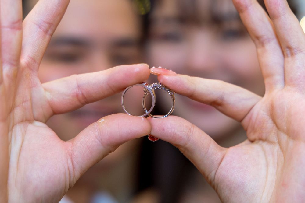 Close-up shot of wedding rings held up against blurred background.