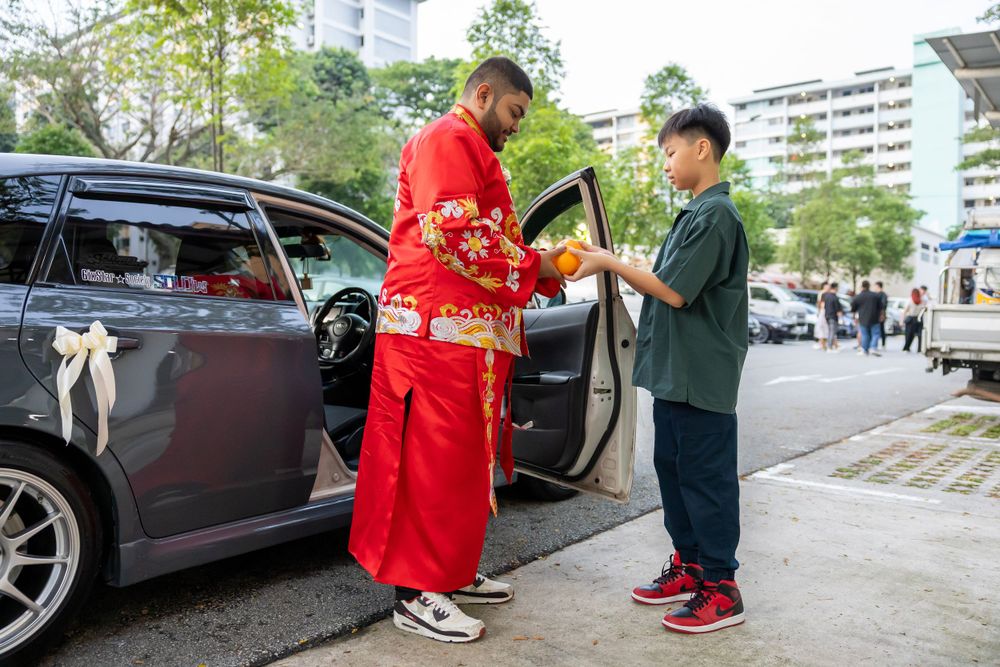 Traditional red-robed figure interacting near a parked car.