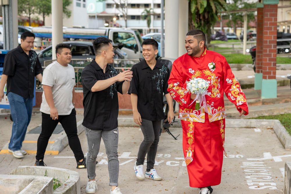 Group walking together outside with one person wearing bright red traditional Chinese ceremonial clothing.