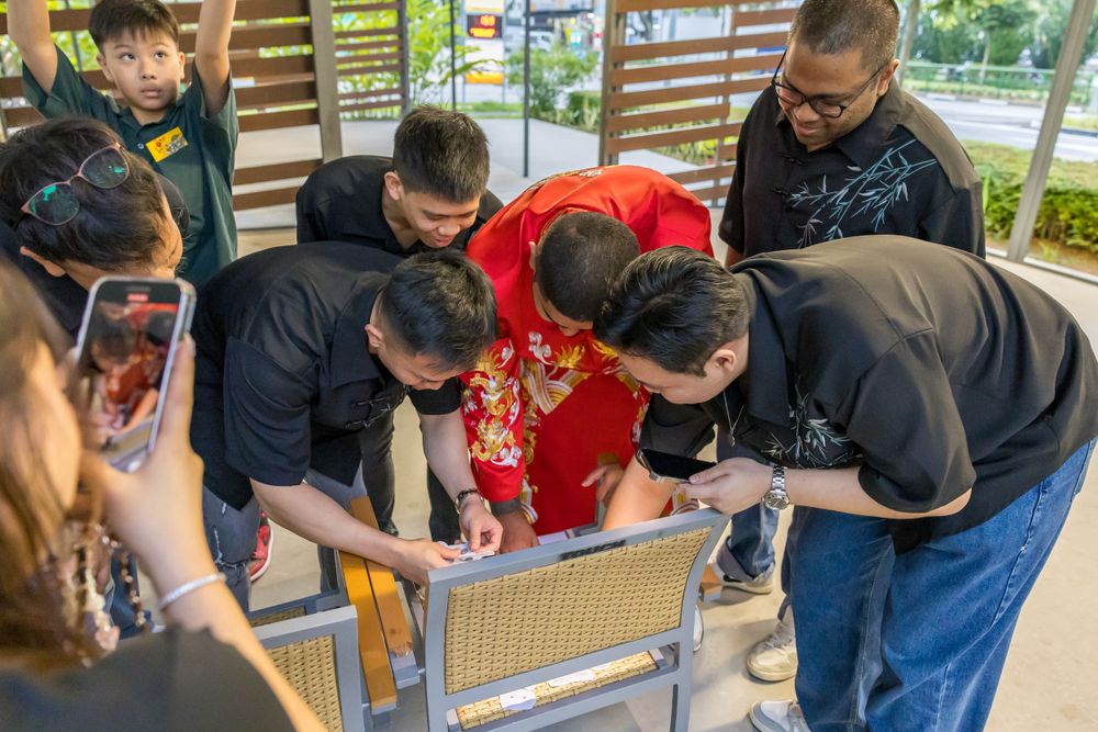 People gathered around examining something together at an outdoor venue.