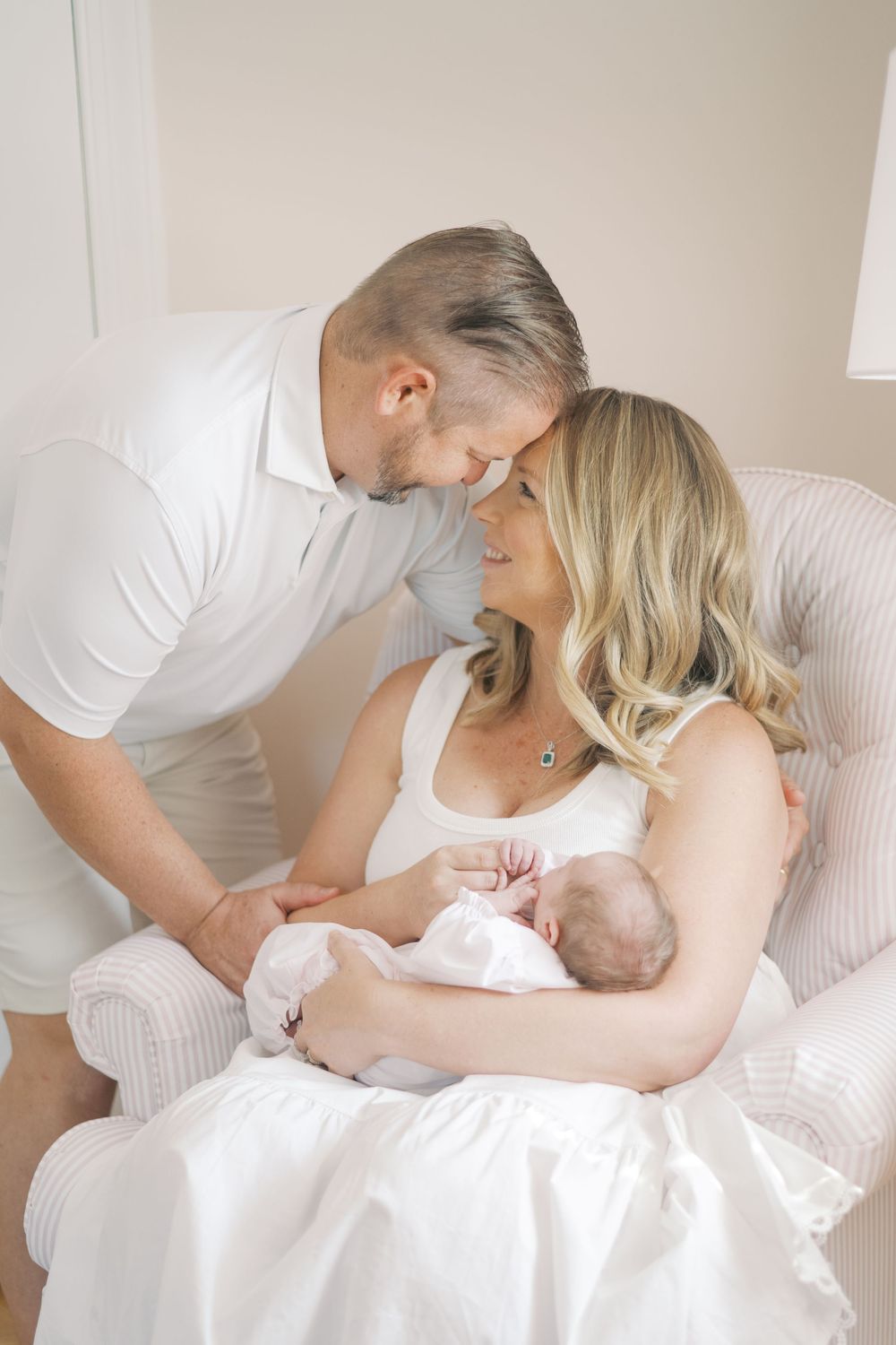 New parents sharing tender moment over newborn baby during indoor lifestyle newborn photography session.