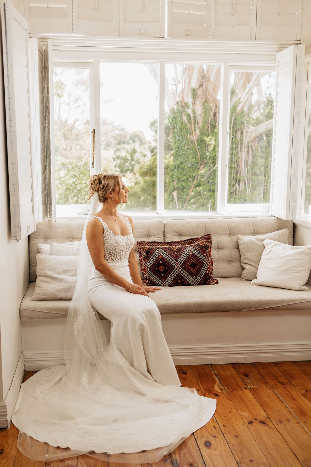 Bright window seat with cushions and a patterned throw pillow in natural light.