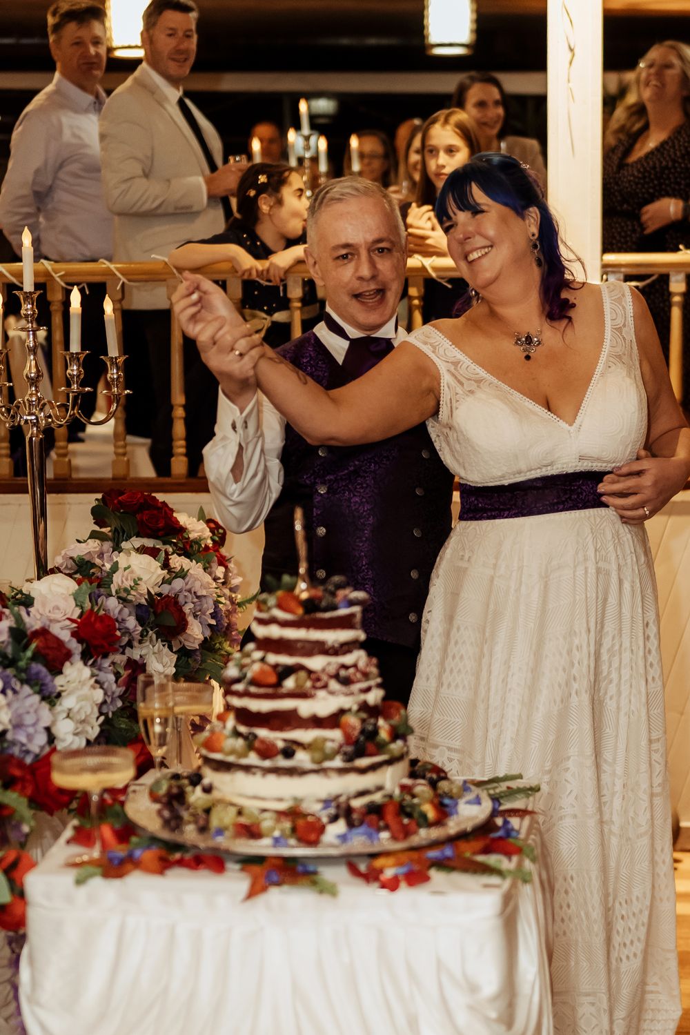 A couple shares a dance at their wedding reception beside an elegant dessert table decorated with candles and flowers.
