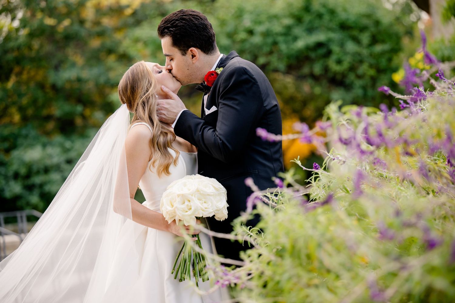 A joyful black and white photograph captures a wedding couple dancing and celebrating on a confetti-filled street.