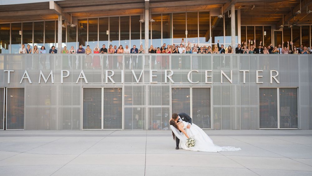 A modern sports arena with illuminated Tampa River Center signage and large glass windows.