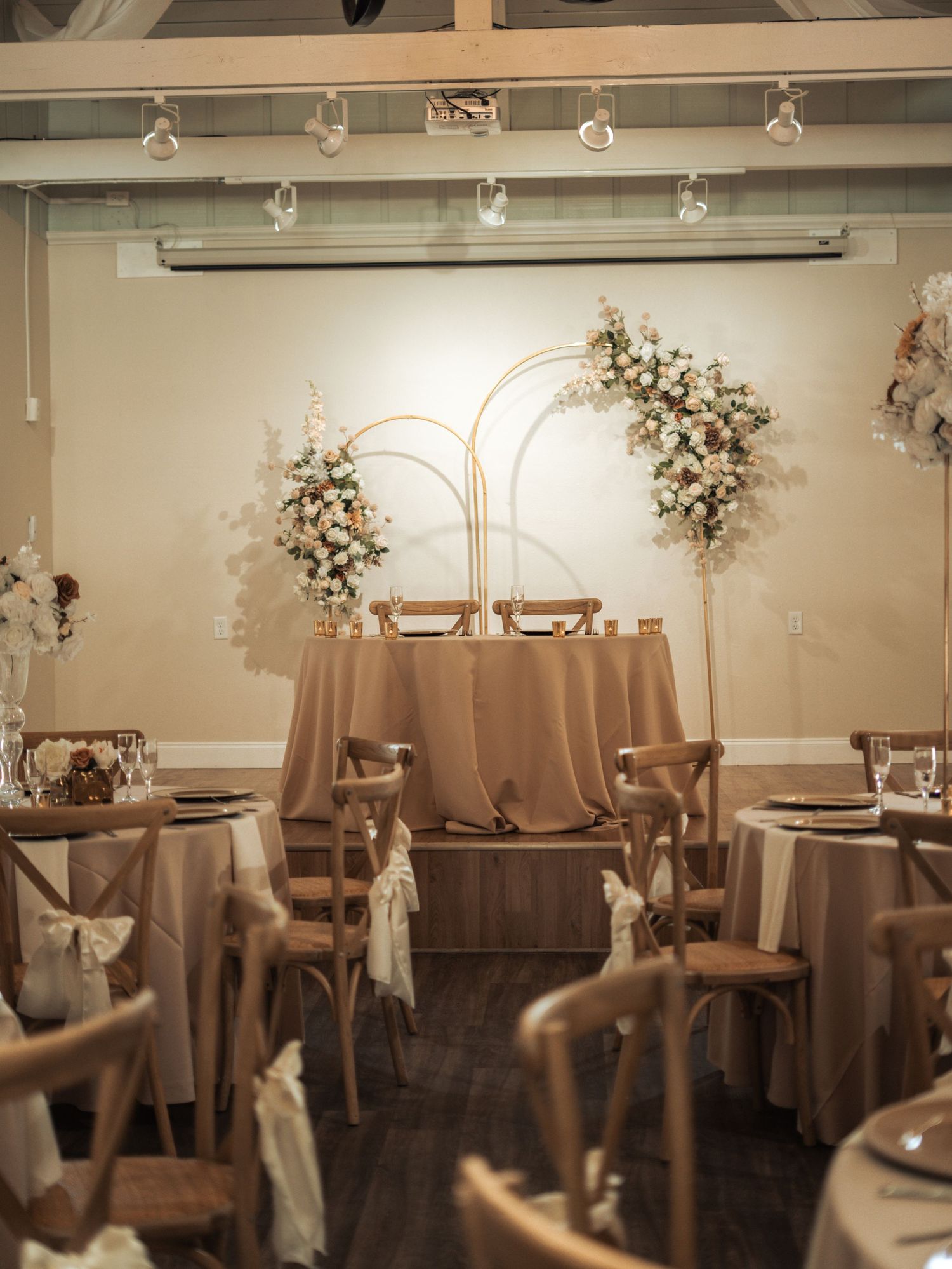 Elegant wedding reception venue with round tables, white floral centerpieces, and soft ambient lighting.