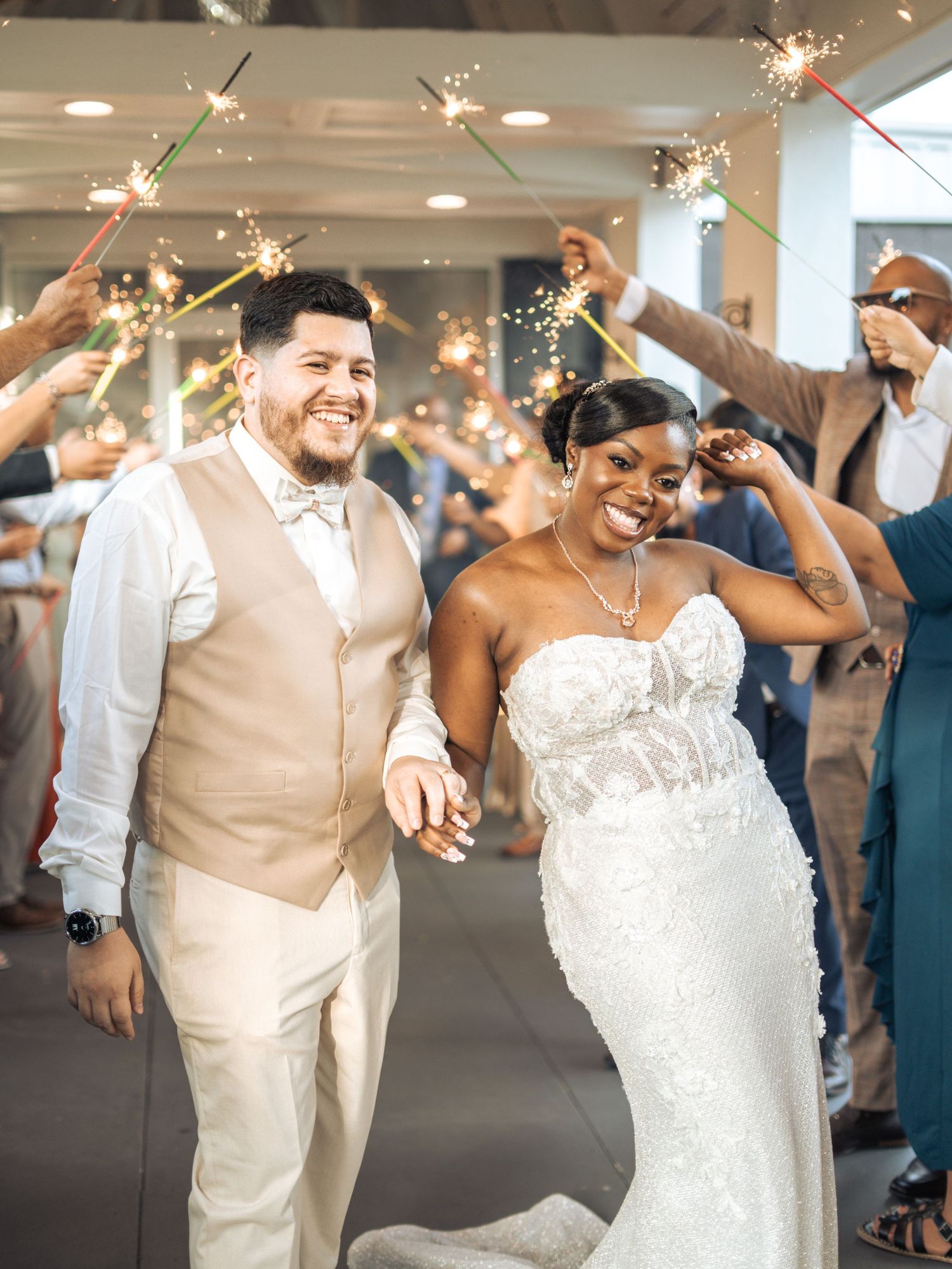 Wedding couple celebrates with sparklers as they exit their reception in formal attire.