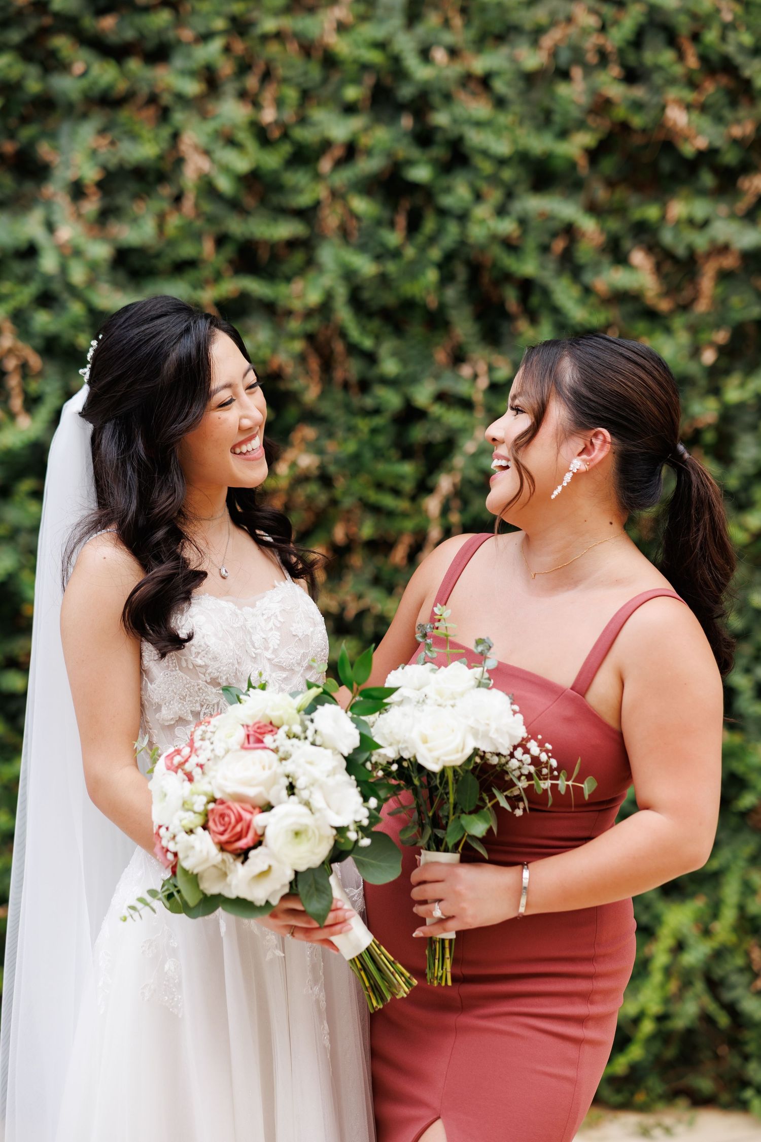 A bride and her bridesmaid share a playful moment during wedding party portraits