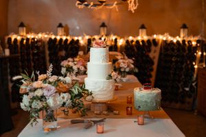 String lights illuminate elegant wedding reception tables and floral centerpieces at a rustic indoor venue.