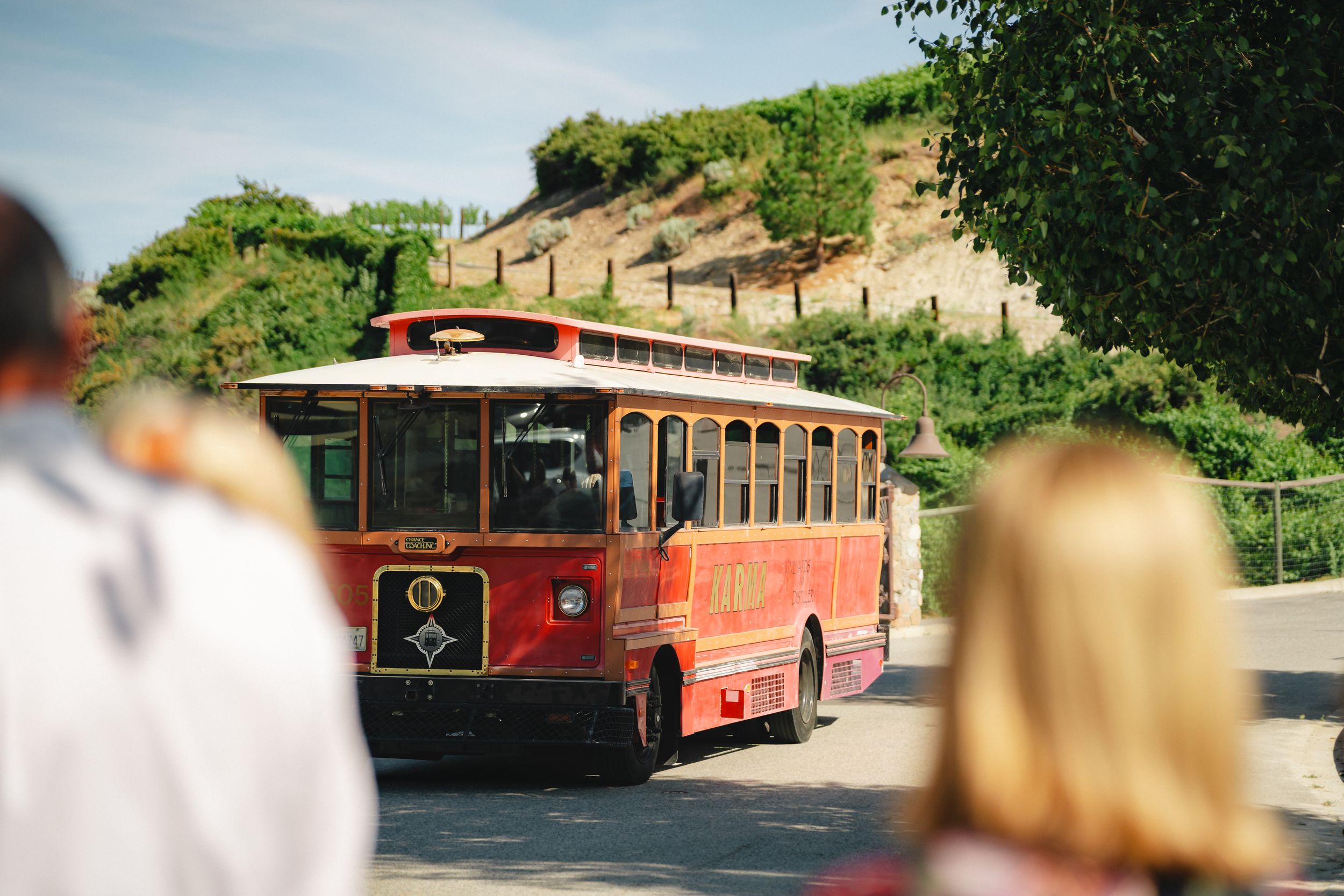Vintage red trolley buses in a row line up at a hillside transit station on a sunny summer day.