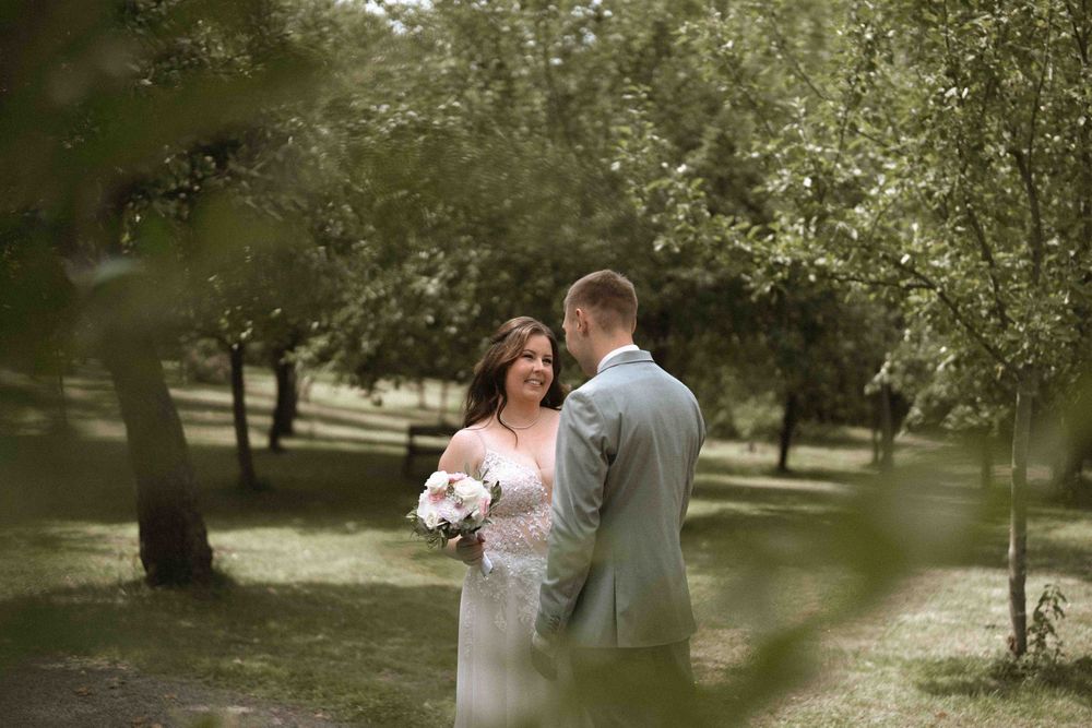A couple shares an intimate moment in an outdoor garden setting with soft natural lighting.
