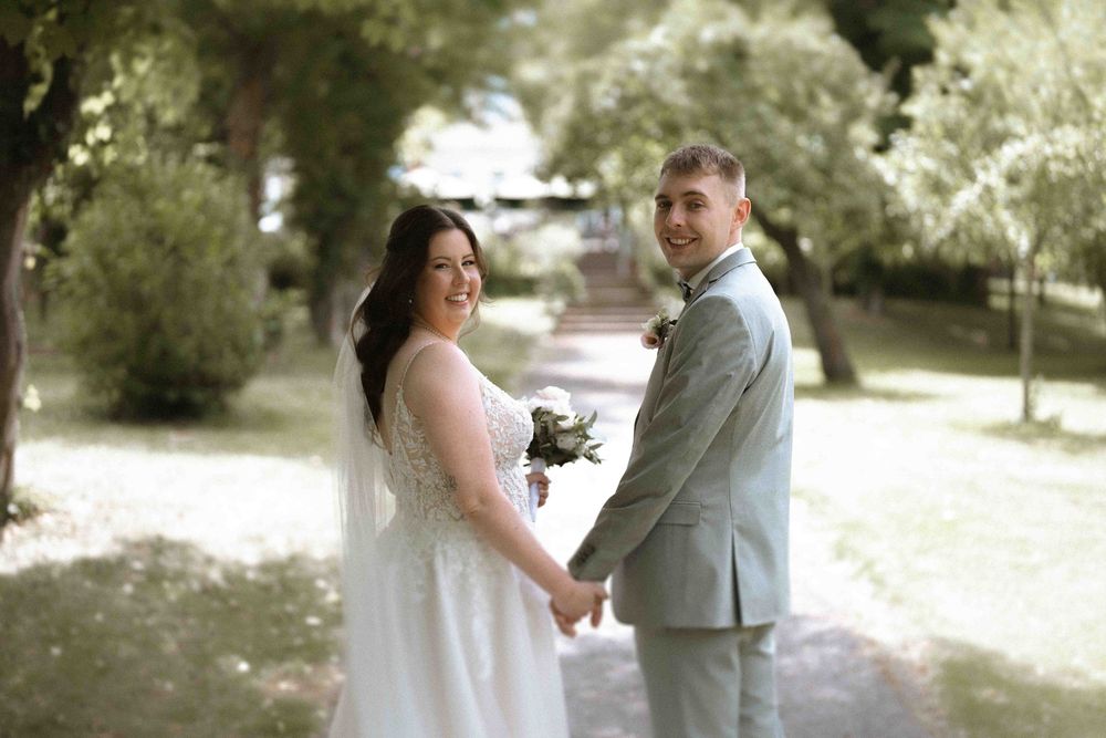 Candid wedding photos show sweet moments between newlyweds in a sun-dappled garden.