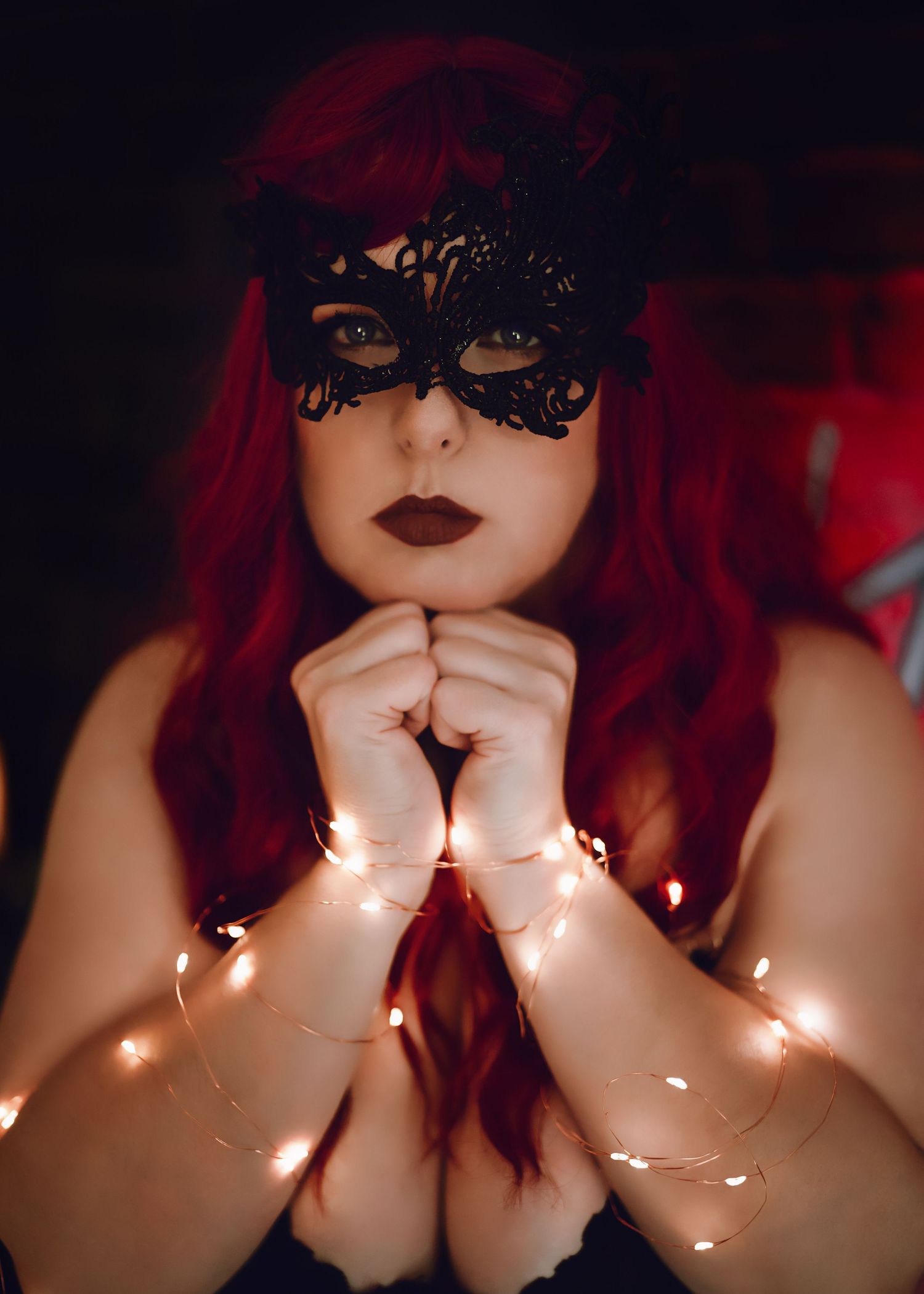 Atmospheric sequence showing someone posing with fairy lights held against their face creating a dreamy red-tinted glow effect.