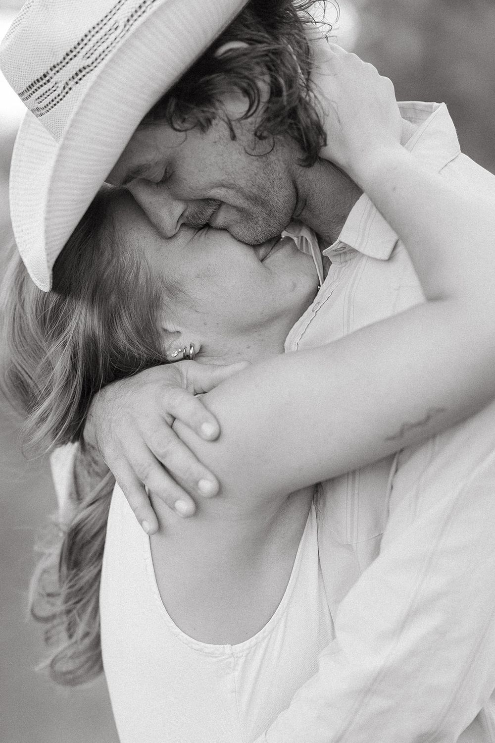 Black and white close-up shots show an intimate embrace between two people wearing white clothing.