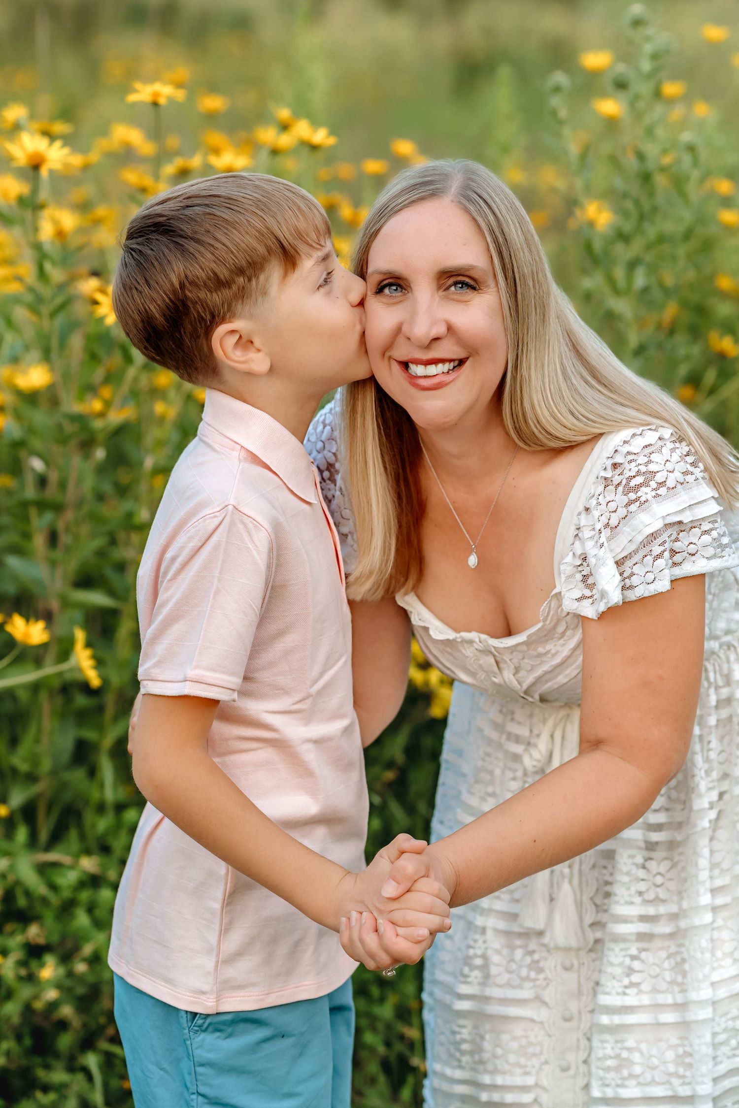 A tender summer portrait showing affection amidst blooming yellow wildflowers in a natural outdoor setting.