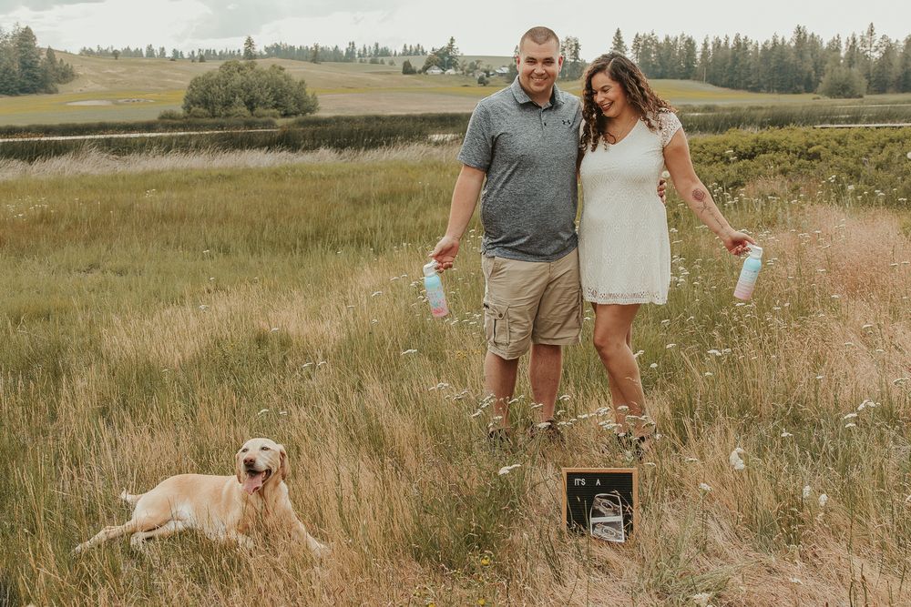 Celebrating gender reveal with pink powder smoke bombs in open field at outdoor photography venue in Spokane, Spokane family photographer