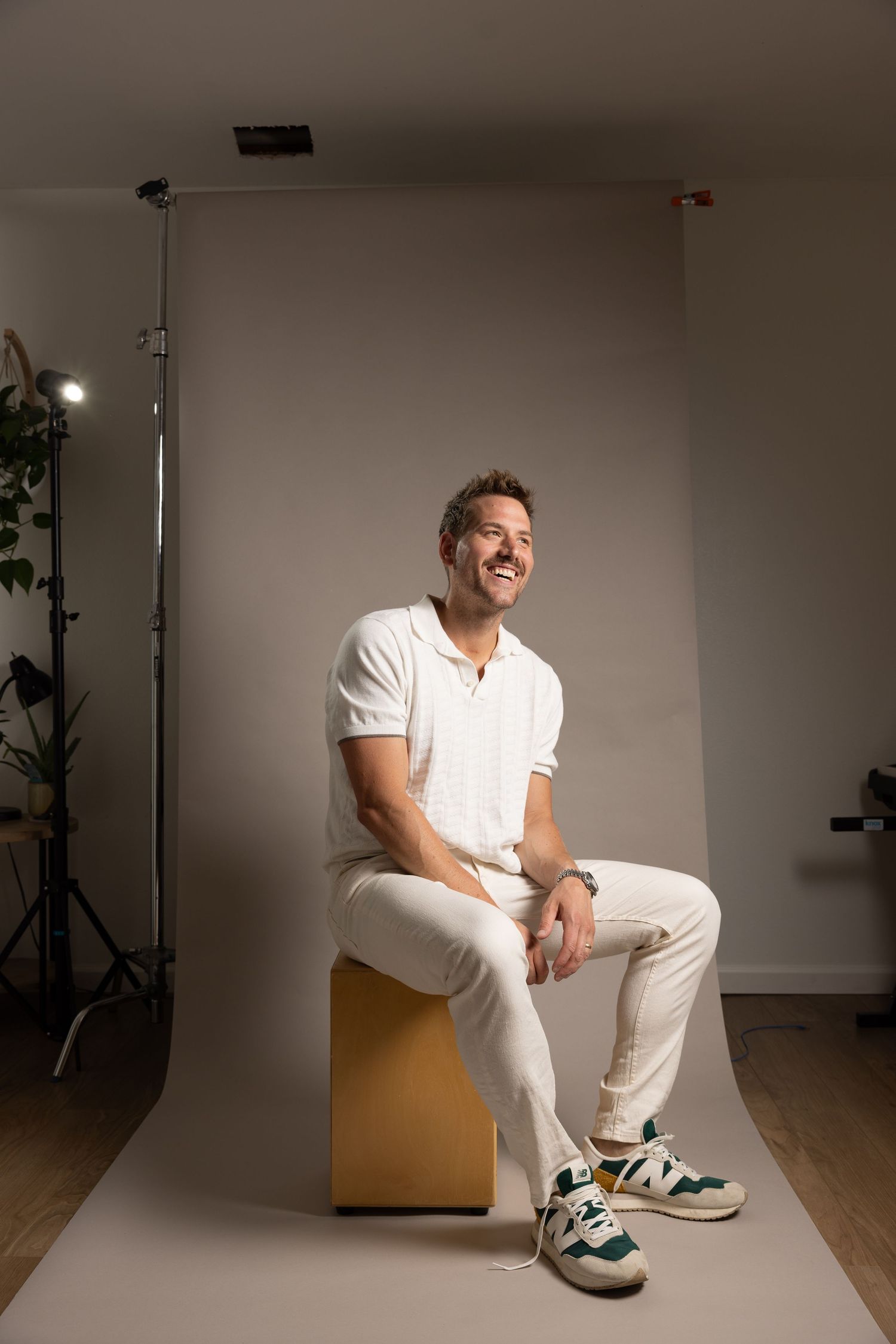 Five artistic studio photographs showing someone in white clothing sitting on a wooden box against a minimalist background.