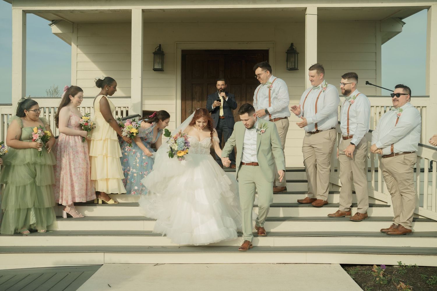 Wedding party gathered on a white columned porch of a southern style venue.
