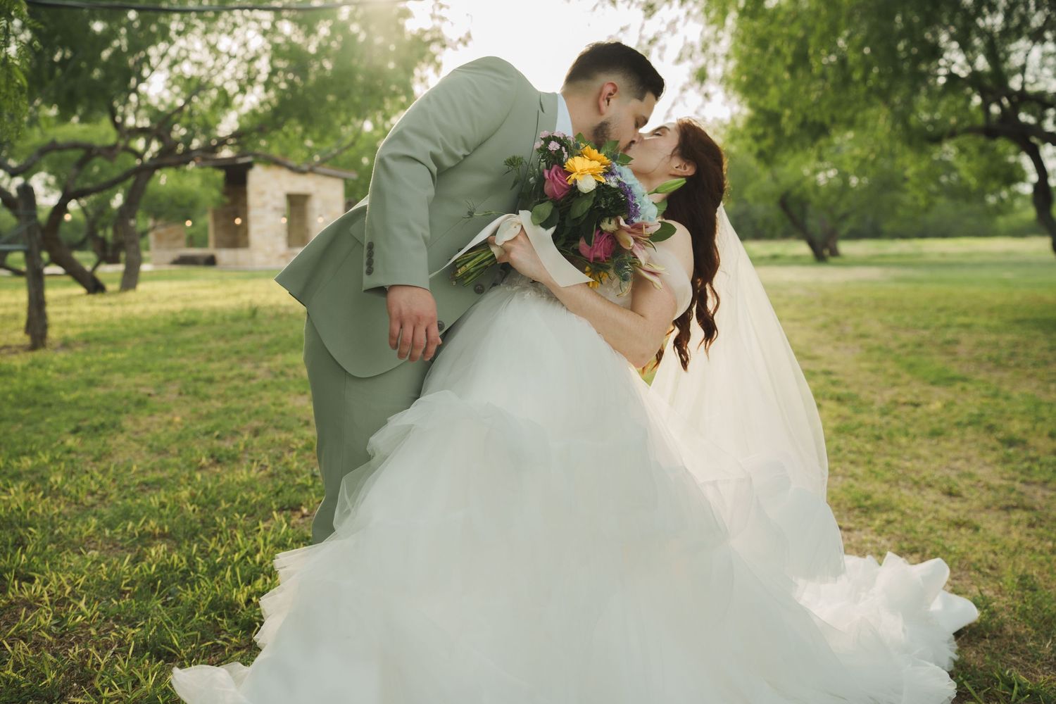 Wedding couple shares joyful moments in a sunlit garden setting.