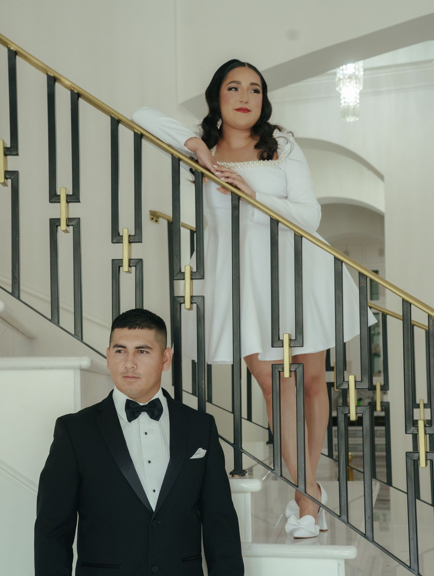 Wedding portraits on a modern staircase with gold and black railings.