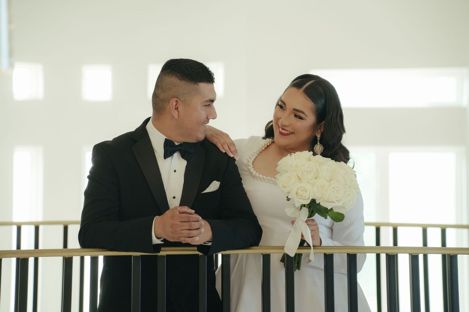 Romantic first look moment captured on an elegant staircase with natural lighting.