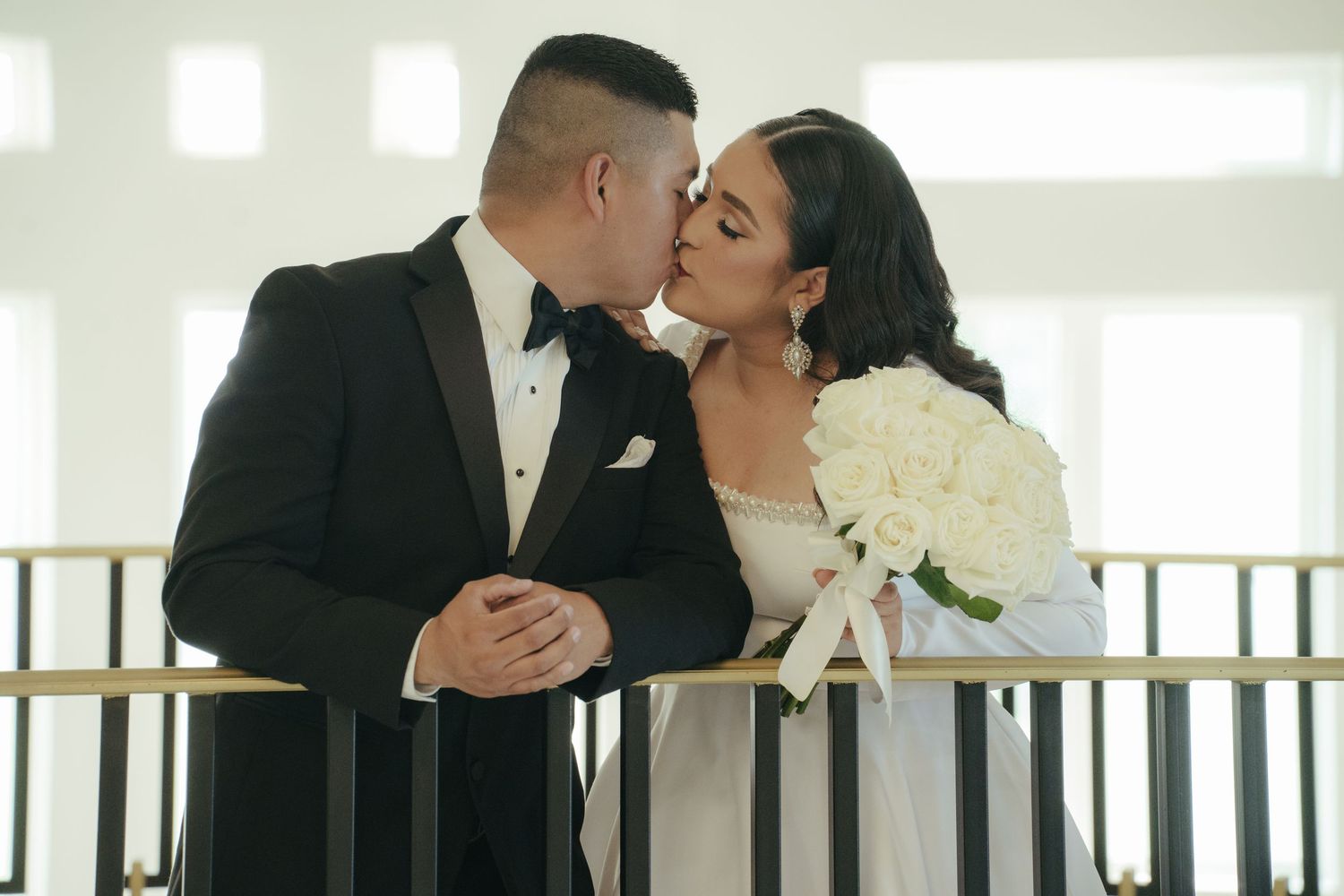 Bride and groom share an intimate moment on a bright, sunlit staircase.