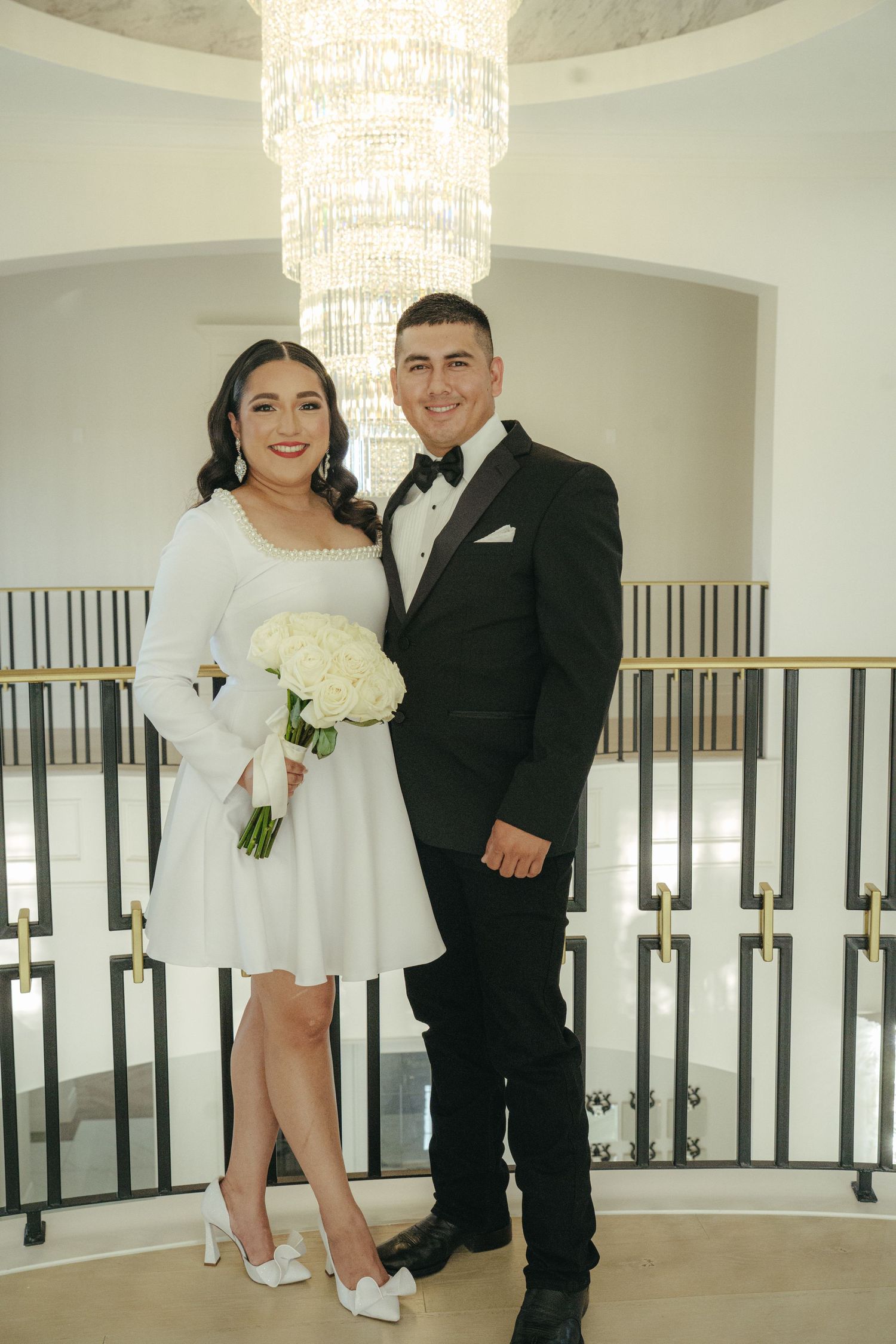 Wedding photos under an elegant crystal chandelier in a modern white interior.