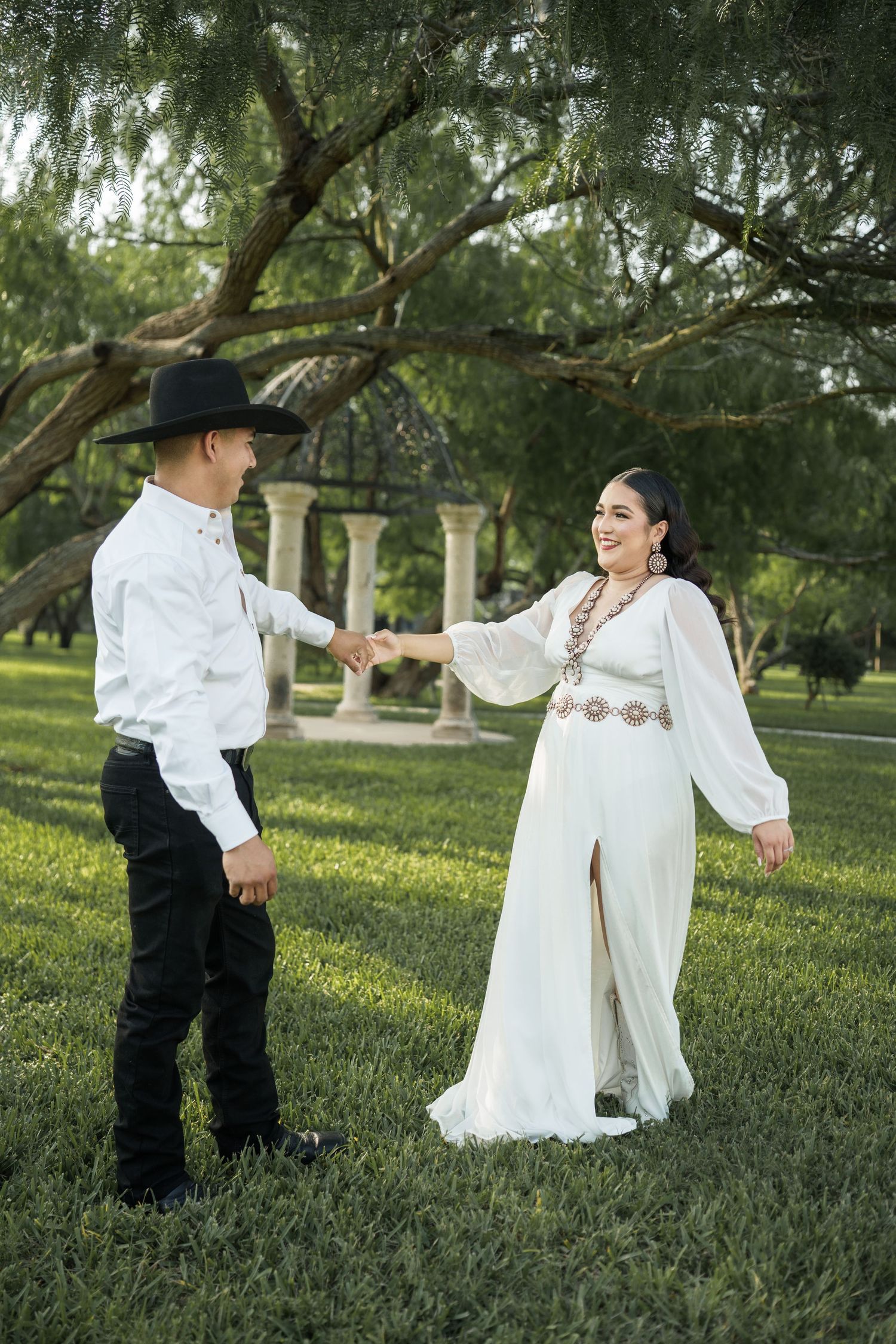 Couple in vintage-inspired outfits dancing in a lush green garden setting.