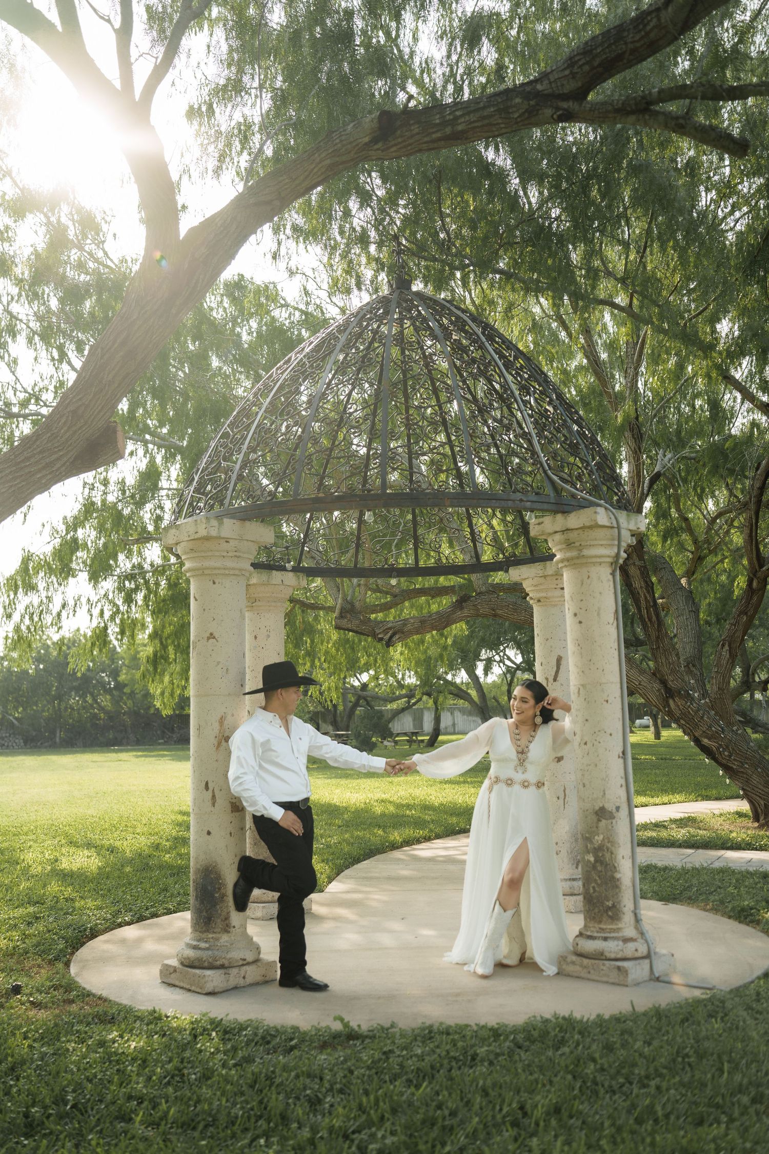 Romantic scene under a gazebo surrounded by weeping willow trees.