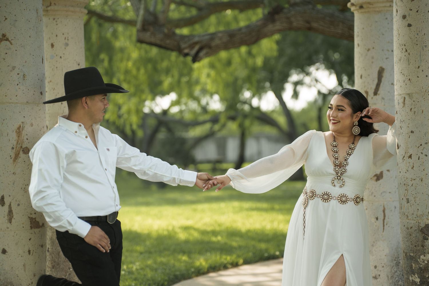 Couple dancing under white columns in an outdoor garden setting.