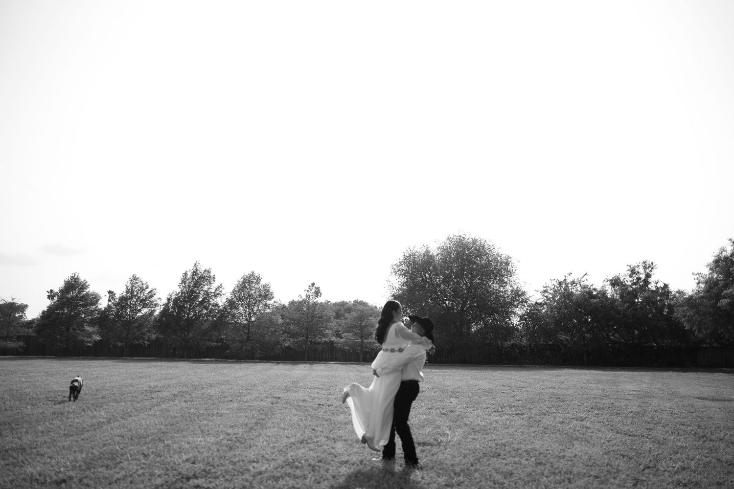 A distant silhouette of people walking across an open field at dusk.