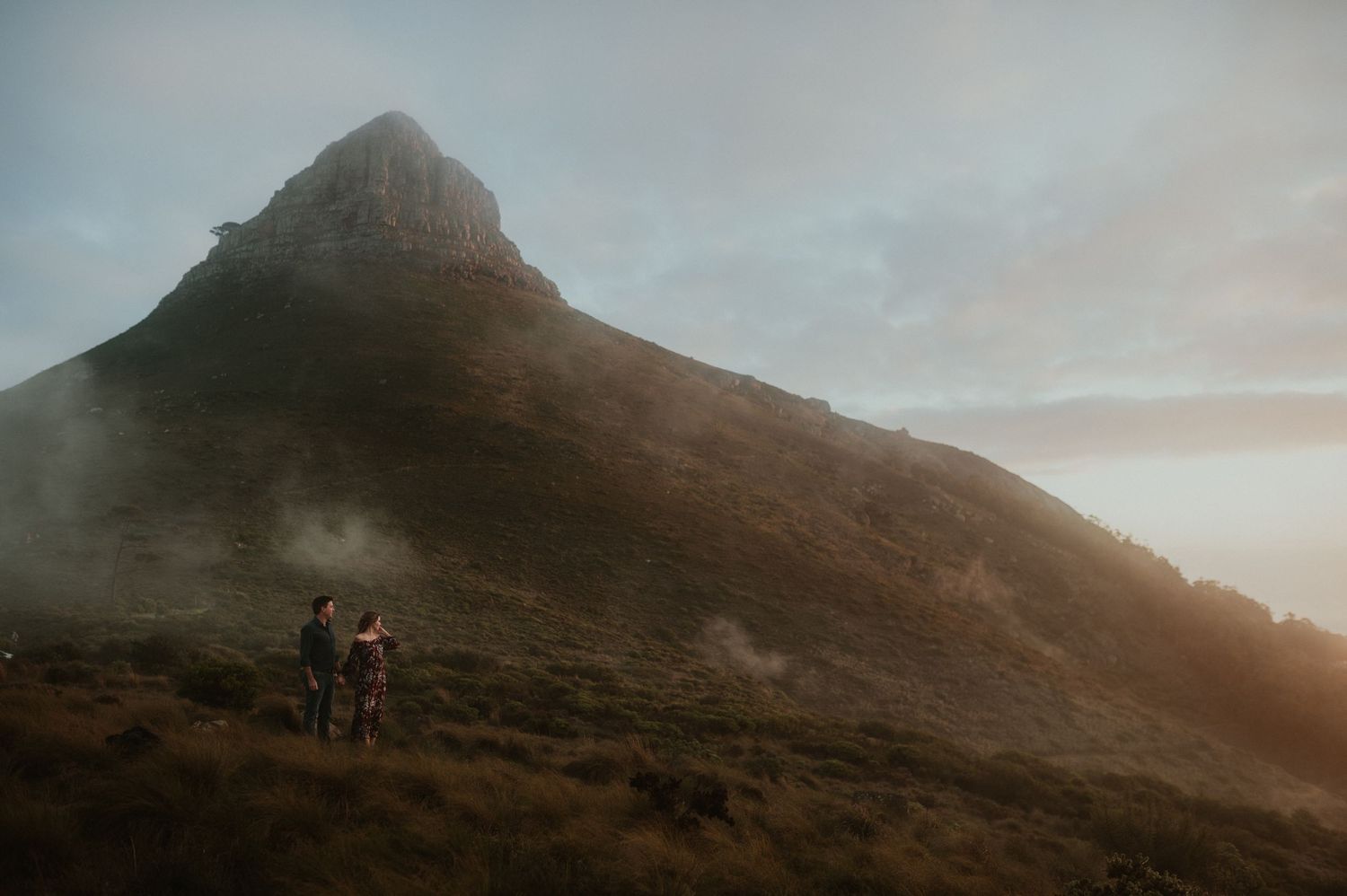 Silhouettes against misty mountain peak during golden hour.