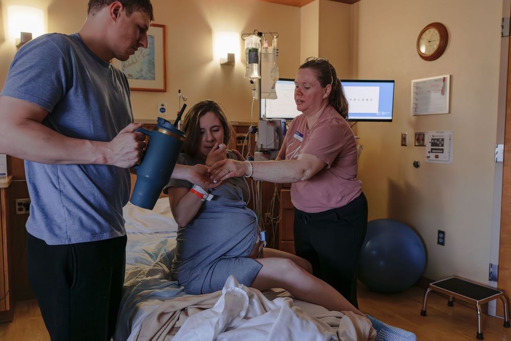 Healthcare providers assist during a labor and delivery process in a warmly lit hospital room.