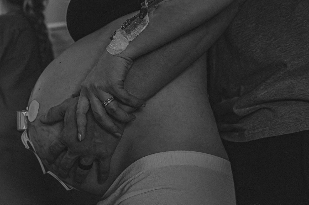 Intimate black and white photo showing hands gently held together in an embrace.