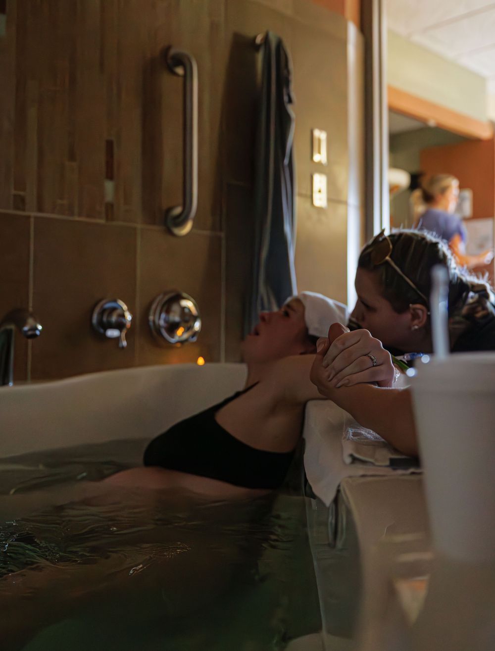 A person relaxes in a therapeutic water bath during labor at a medical facility.