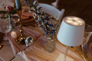 Table decorations featuring small lamps, crystal glasses, and delicate floral arrangements.