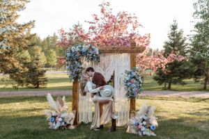 Romantic garden ceremony setup with vintage door backdrop and blue hydrangea floral arrangements.