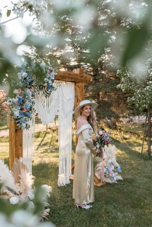 Dreamy garden wedding scene with macrame backdrop and pastel floral arrangements in golden sunlight.