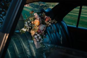 A delicate floral bouquet rests on the leather backseat of a classic car.