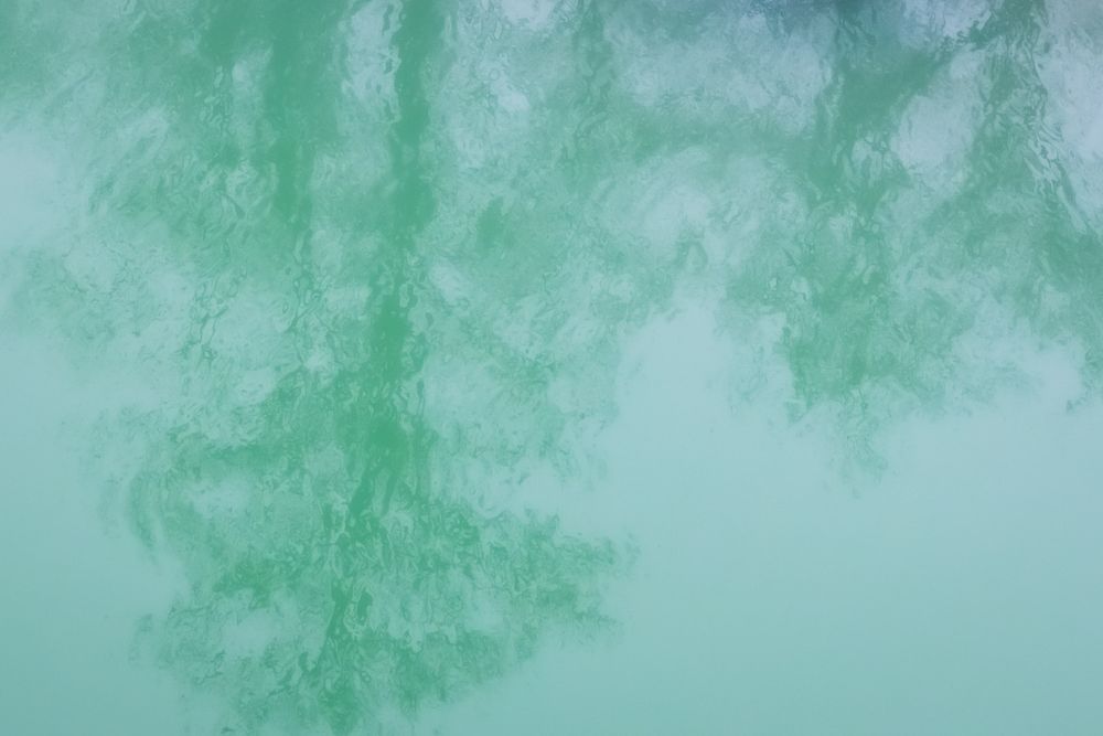 Soft green reflection of trees mirrored in calm, turquoise-tinted water surface. Buffalo National River