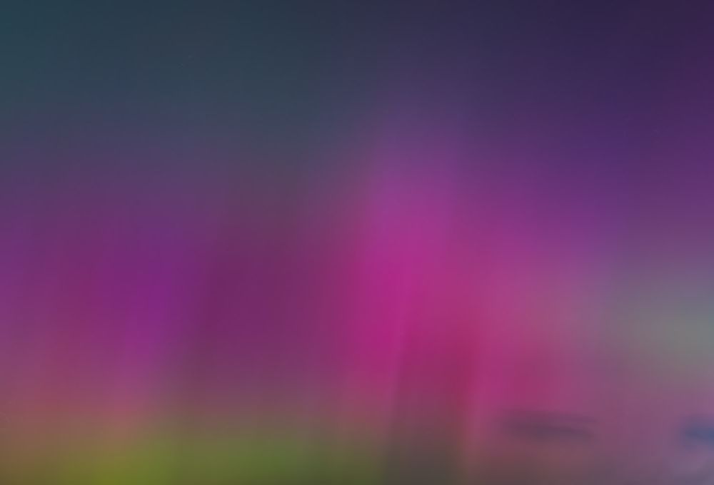 Vibrant pink and magenta northern lights aurora borealis filling the night sky.