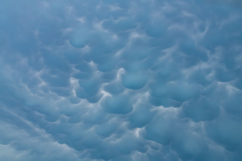 Dramatic mammatus clouds form unusual pouch-like formations across a blue-gray stormy sky. Indian Point, Missouri