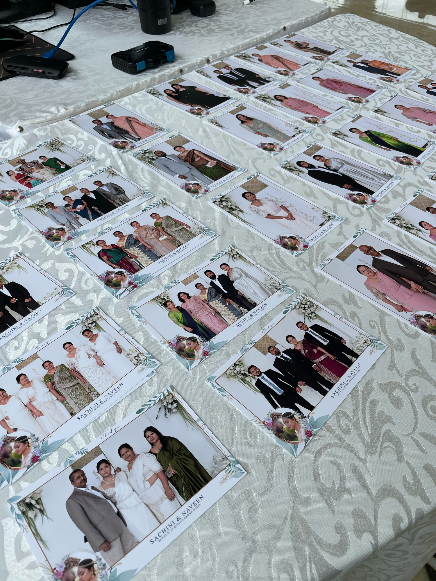 Wedding photo prints arranged on a white textured tablecloth showing various celebration moments.