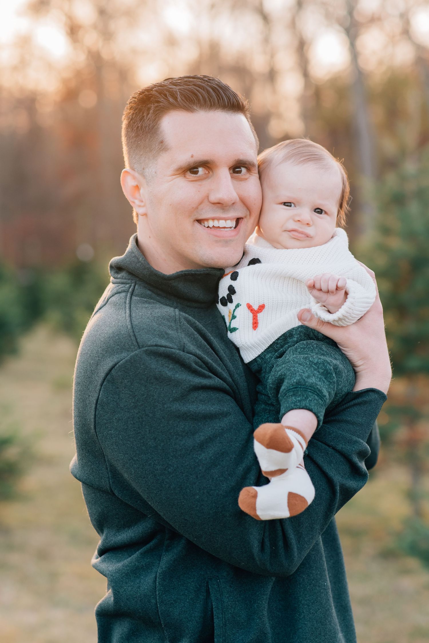 A father is cheek to cheek with his newborn son at a tree farm in wall NJ.