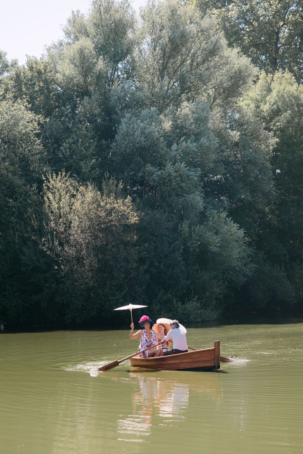 Small wooden boats floating on a green lake surrounded by trees.