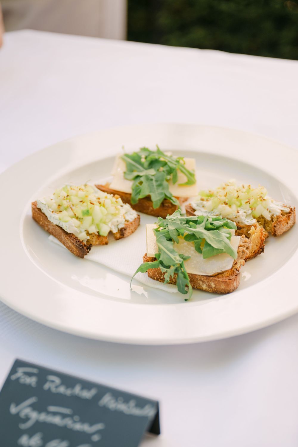 Slices of artisanal toast topped with egg salad and fresh microgreens on white plates.